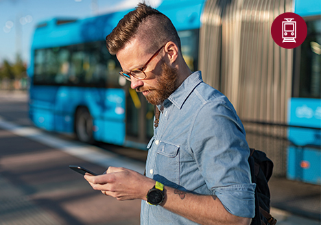 Foto von einem Mann vor einem Bus, der auf sein Smartphone schaut.