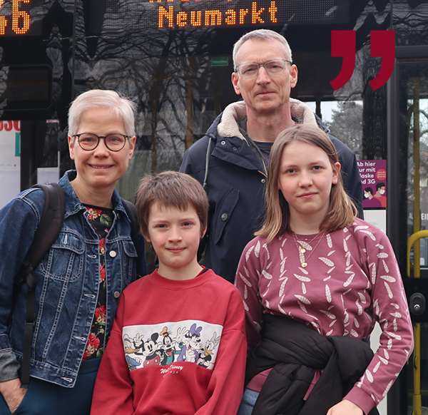 Foto einer vierköpfigen Familie vor einem Linienbus.