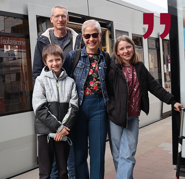 Foto einer vierköpfigen Familie vor einer Straßenbahn.