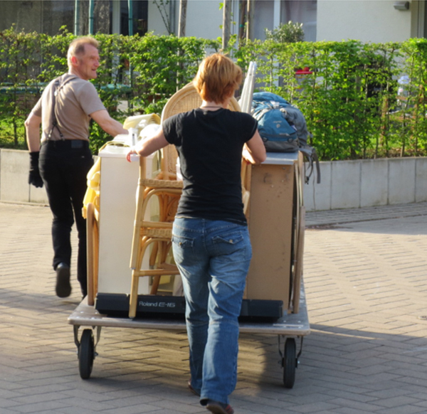 Foto mit Transportkarren auf dem Möbel in der autofreien Siedlung von einem Mann und einer Frau transportiert werden. 