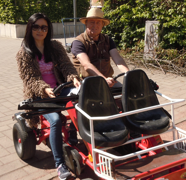 Mann und Frau fahren in der autofreien Siedlung Stellwerk 60 mit einem großen Tretmobil.